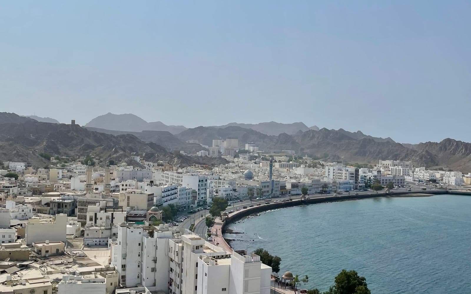 Aerial view of Muscat's coastline framed by rugged mountains, Oman