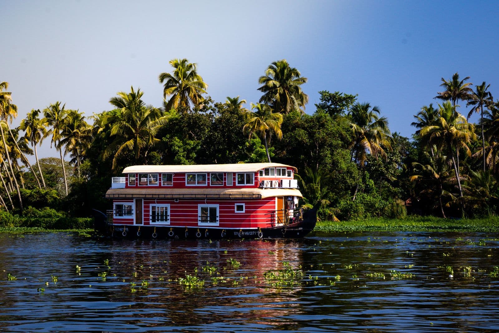 A traditional Kerala houseboat cruising a palm-lined backwater channel near Alleppey