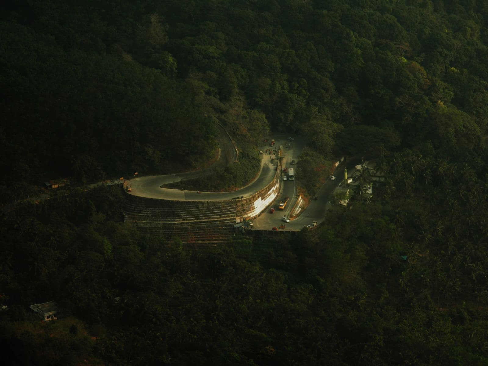 A narrow road curving through dense green forested hills