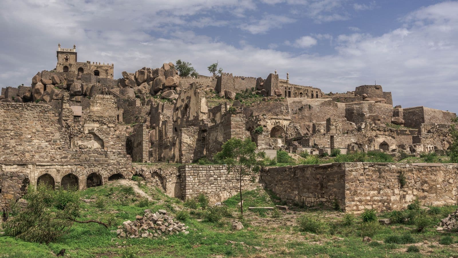 The stone ramparts and gateways of Golconda Fort under a clear blue sky