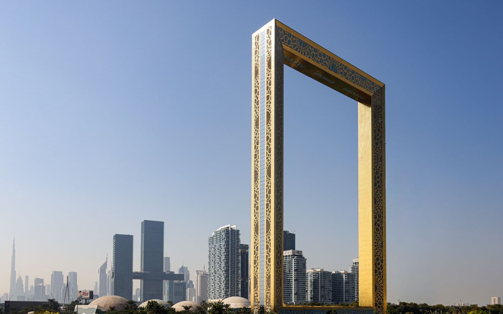 The gold Dubai Frame at Zabeel Park with the city skyline behind it