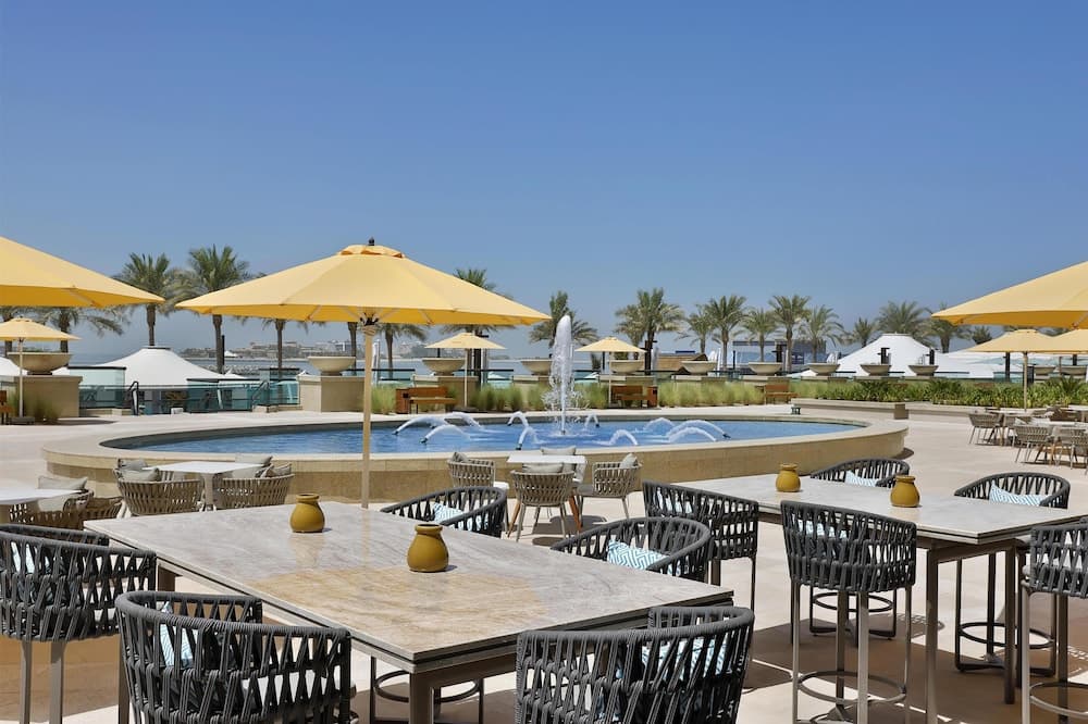 Outdoor terrace with umbrellas by the pool at Hilton Dubai Palm Jumeirah