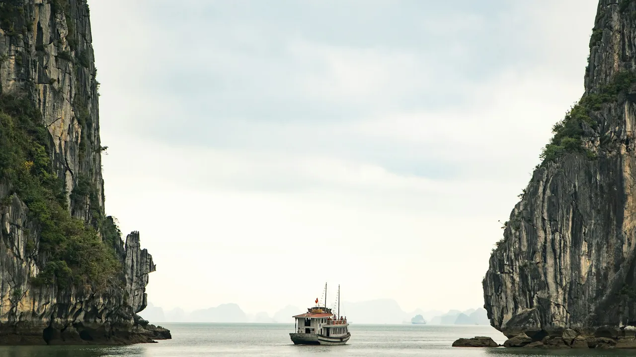 Cruise boat passing karst cliffs in Ha Long Bay